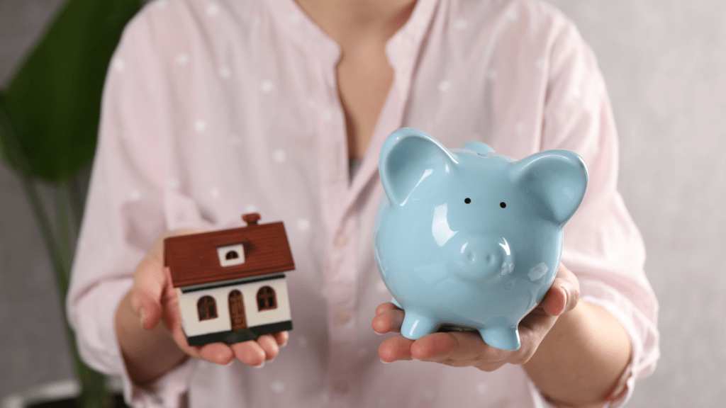 Piggy bank and house model representing saving for a down payment for First Time Home Buyers
